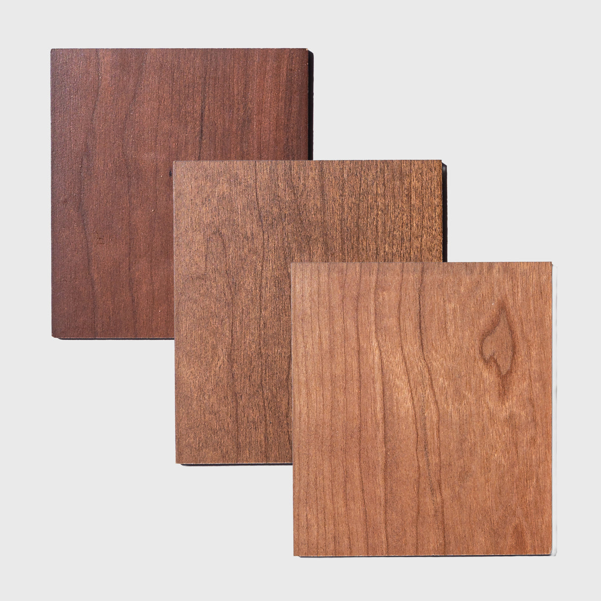 three wooden squares with different finishes applied on a white background