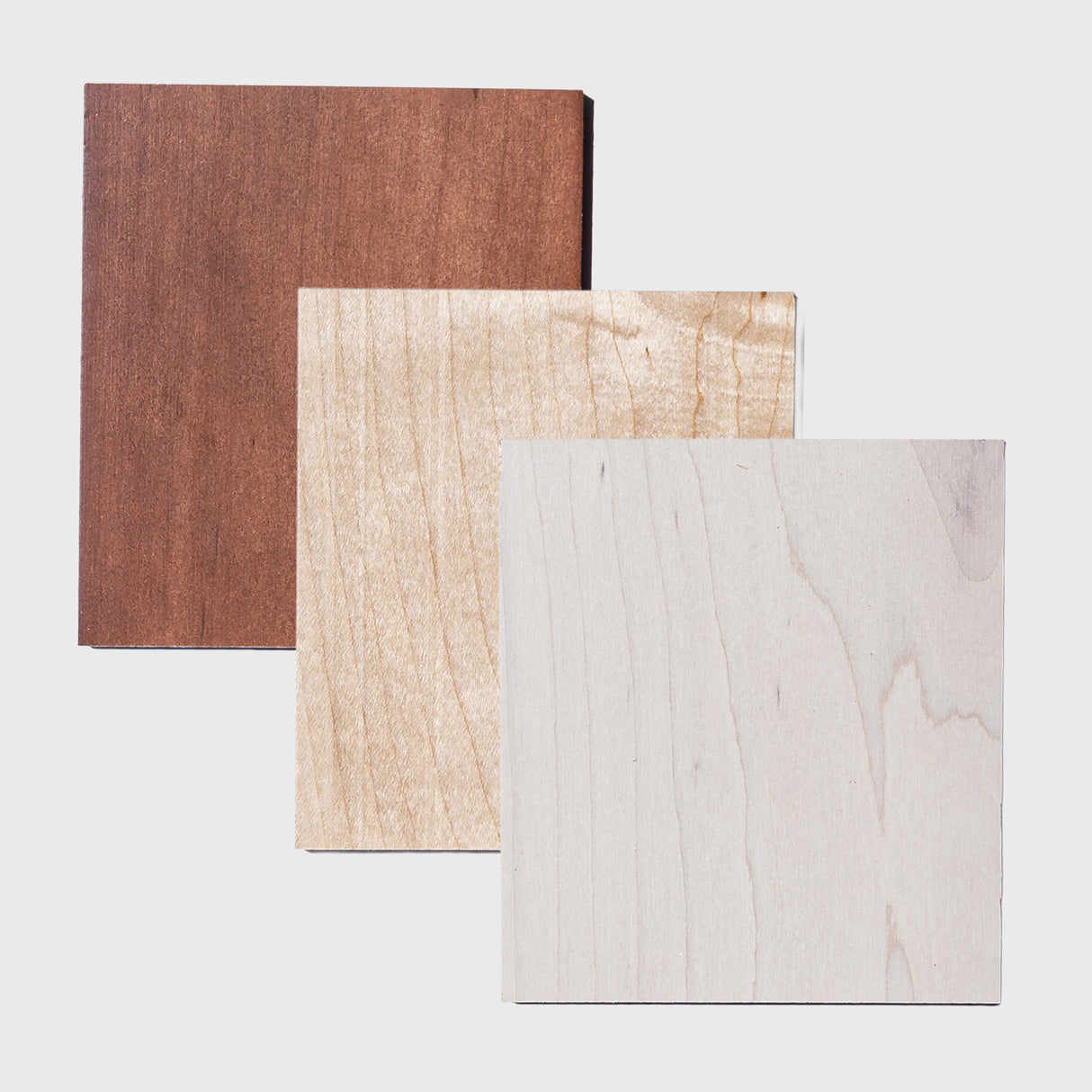 Three maple wood squares with different finishes on a light gray background