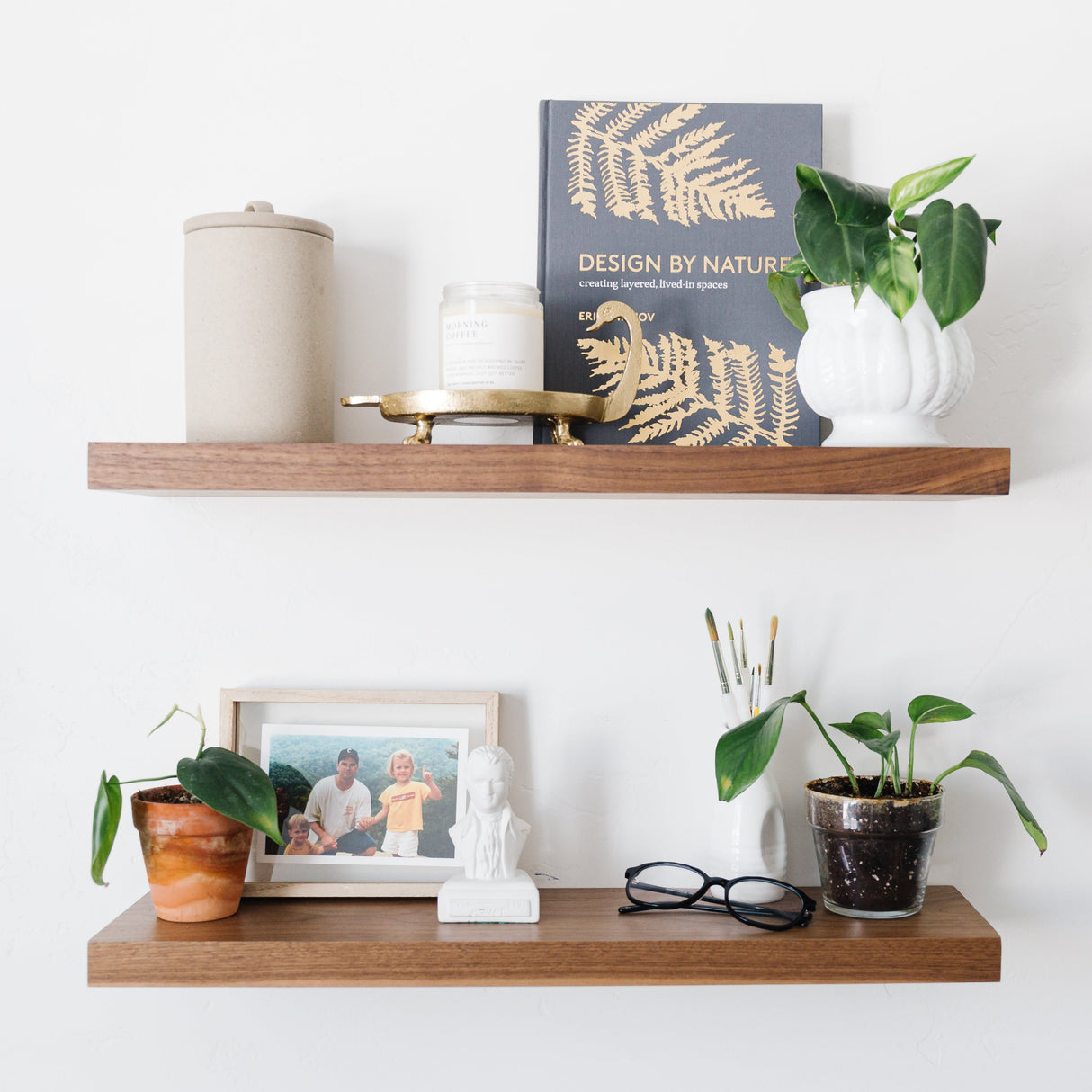Wooden shelves with decorative items including a book, plant, and photo frame on a white wall.