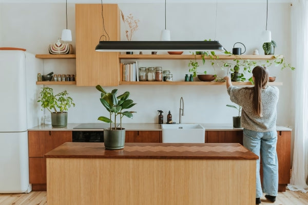 A woman displaying items on kitchen shelves