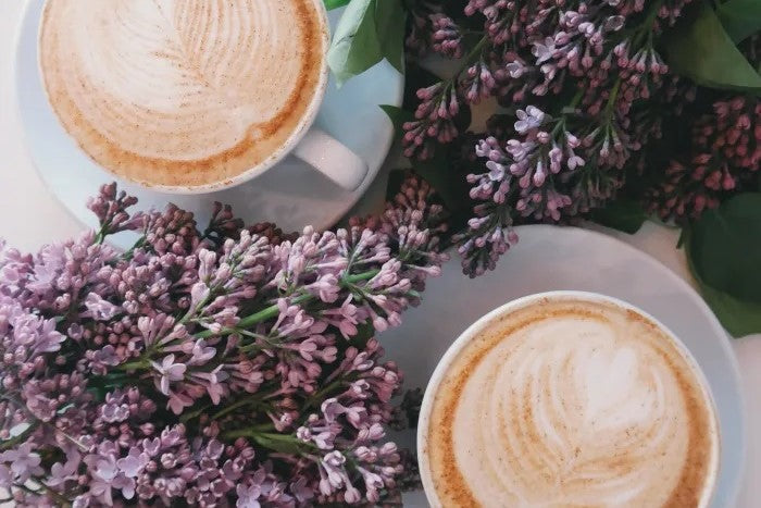 Two coffee mugs with flowers around them