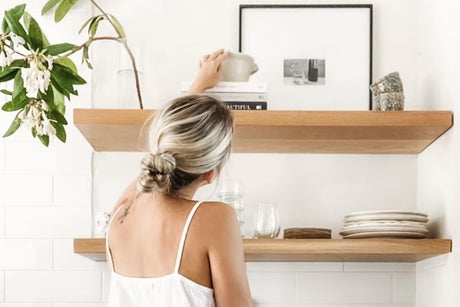 Woman placing decor on kitchen floating shelves