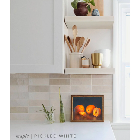 maple floating shelves in a kitchen with the pickled white finish applied decorated with kitchen utensils, a plant, charcuterie board, and vases